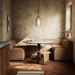 Dining banquette styled in a warm, textured dining nook with a round table and pendant light