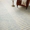 Close-up angled view of blue and cream striped rug under small round side table and leather armchair