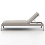 Outdoor setting with Sherwood Modern Stone Grey Outdoor Chaise beside pool with hat and green scarf on cushion