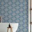 Wallpaper applied on wall behind freestanding tub with window blinds and wooden stool in modern bathroom