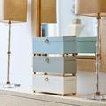 Stacked rectangular boxes in gray, seafoam, and white finishes on console table with lamps and mirror