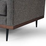 Close-up of wooden base and front corner of chair base with black tapered leg and gold tip