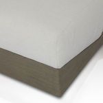 Corner detail showing junction of white upholstery and light wood base with fine wood grain