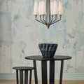 Chandelier hanging above round table with sculptural black ceramic bowl and matching stool