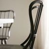 Close-up side view highlighting curved backrest and distressed wood texture of stool
