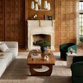 Heritage Clay / Natural rug in a living room with wood-paneled walls, cream sofa, and green velvet chairs