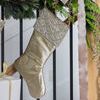 Gold stocking hanging on staircase railing decorated with garland with champagne pine sprays and velvet ribbon