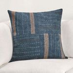 Blue patchwork pillow styled on white cushioned chair for scale and context