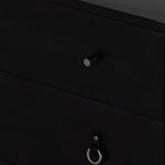 Close-up of leather ring handles attached with metal rivets on black wood drawer