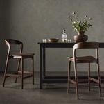 Lifestyle room setting with two bar stools paired with modern black table and decorative vase