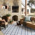 Easton Ivory / Denim rug styled in outdoor patio seating area with stone wall and wicker chairs