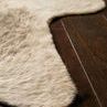 Close-up view of the rug’s beige textured fiber edge resting on dark wood floor