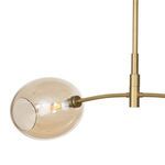 Close-up view of the pendant’s central mounting and curved arm connection in natural brass finish