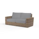 Two-seat outdoor loveseat with weathered tobacco wicker frame and light gray cushions