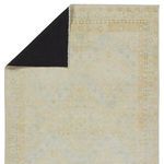 Backside of rug showing black woven fabric and folded corner to reveal front Persian diamond pattern