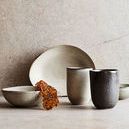 Mame Cups paired with matching ceramic bowls and a plate in natural light on a textured surface