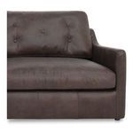 Close-up of one armrest and seat cushion emphasizing button tufting and leather texture