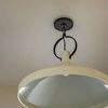 Close-up of pendant’s aged iron ceiling mount and hanging loop with view slightly from beneath shade