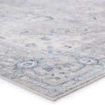 Close-up angled view showing texture-rich high-low pile and detailed floral pattern in muted blue and gray