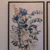Full frontal view of second floral artwork with blue and tan flowers in black frame hanging on wall