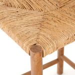 Detailed view of banana leaf weaving and rounded wooden leg corner on seat edge