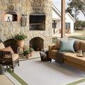 Easton rug placed on a patio under outdoor furniture by stone fireplace and wooden porch