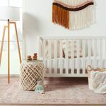 Rug placed in a nursery scene with white crib, woven basket, and wooden floor lamp