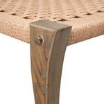 Close-up of front corner joint where woven seat meets curved wooden leg with visible wood grain