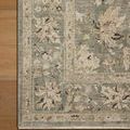Close-up corner of Briar Dune Mist Rug on wood floor showing floral border detail
