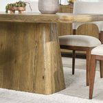 Orlando Dining Table in room context with light brown oak base, dining chairs, rug, and decorative centerpiece