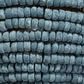 Extreme close-up of textured gray mango-wood beads strung tightly in rows