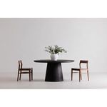 Two blackened oak Owing Dining Chairs flanking a black round dining table in minimalist setting