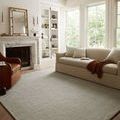 Polly Fog / Wheat rug styled in a living room with beige sofa, leather chair, and natural light