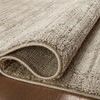 Rolled-up section of the rug exposing the ribbed weave and light backing fabric
