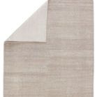 Top corner of light taupe rug folded to reveal lighter underside texture and construction