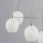 angled view of three white marbled globe shades hung from polished nickel rods and chains
