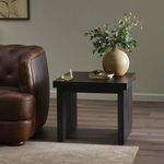 Warby End Table shown in black finish by leather armchair styled with a vase, glass, and books
