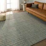 Rug styled in a living room next to brown leather sofa and soft natural light