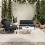 Outdoor seating arrangement with two Salma chairs and matching loveseat on stone floor with potted plants