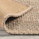 Bent corner reveals backing fabric and thickness of the handwoven jute rug