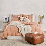 Styled bedroom scene with quilt set layered with patterned and textured throw pillows and plush knit blanket