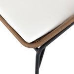 Detail of white seat cushion edged with woven fawn material on black metal frame