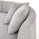 Detail of two plush cushions resting against the gently curved armrest in grey fabric