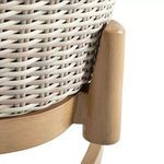 Close-up of light wood base leg connecting to wicker frame