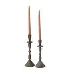 Two metal Bristol candlesticks side by side each holding a beige taper candle, showing size variation