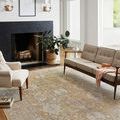 Rug in modern living room with beige sofa, cream armchair, indoor plant, fireplace, and natural light