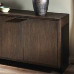 Close-up of dark iron pulls and rubbed black oak wood grain with decorative vase on surface