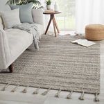 Rug styled in bright living room under gray sofa, side table, and pouf with white wood flooring