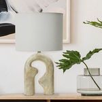 Eclipse Resin Table Lamp styled on wooden table with glass vase and green leafy plant in a minimalistic room setting