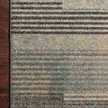 Close-up of the rug’s edge and pattern showing color transitions and dark binding against hardwood